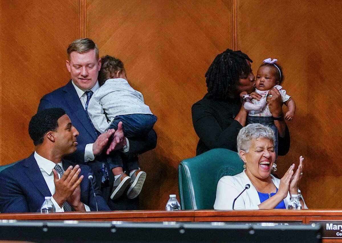 Nwamaka Unaka, chief of staff to council member Carolyn Evans-Shabazz kisses her daughter, Muna, as Paul Young, chief of staff to council member Edward Pollard,holds Fitz after the paid parental leave policy passes with a unanimous vote during a city council meeting as Mayor Sylvester Turner requested all City Council members to return to the chamber at City Hall on Wednesday, April 13, 2022 in Houston, the first such requirement since May 2020.