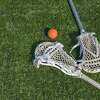 Lacrosse sticks and ball on artificial turf.