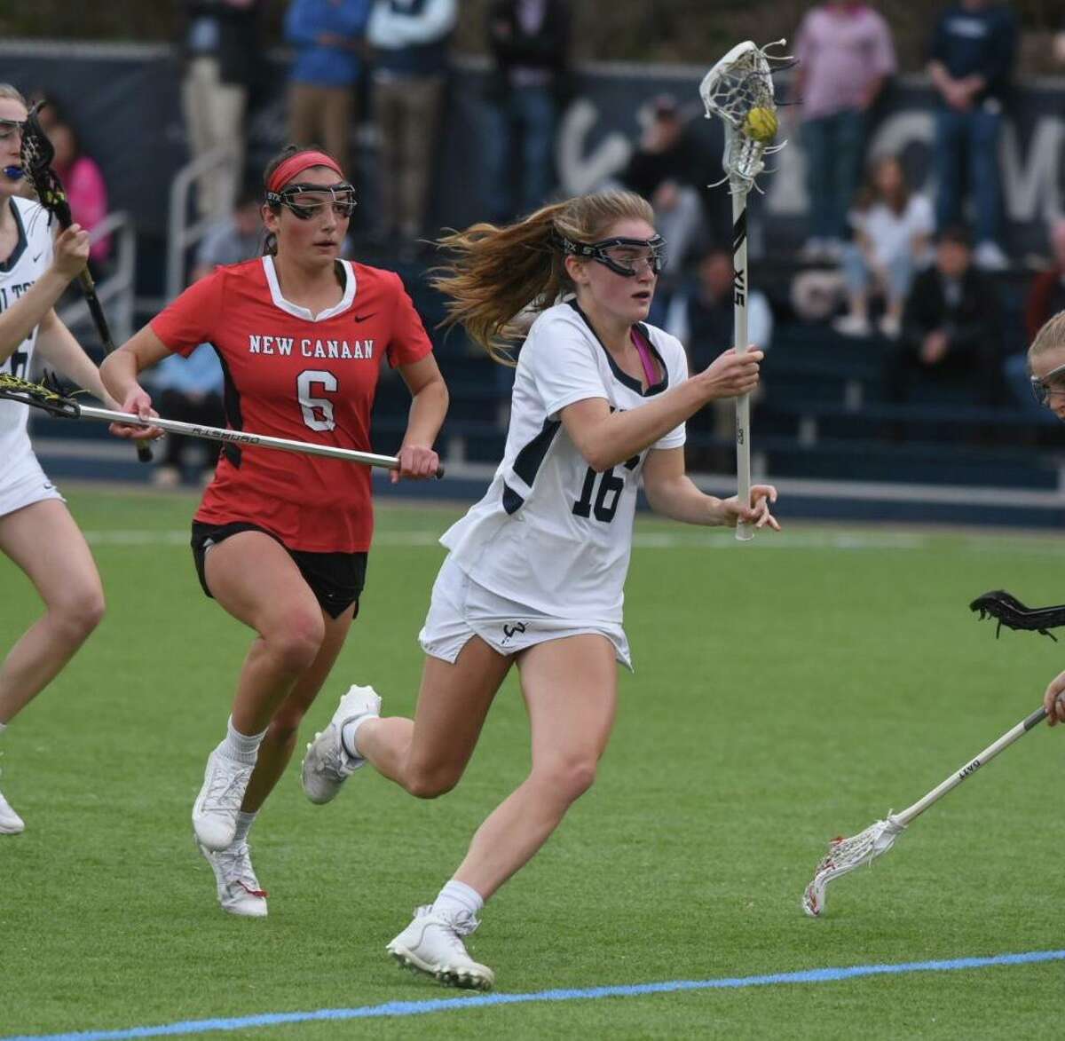 Wilton’s Addison Pattillo (16) carries the ball while pursued by New Canaan’s Kaleigh Harden (6) during a girls lacrosse game on Wednesday in Wilton.