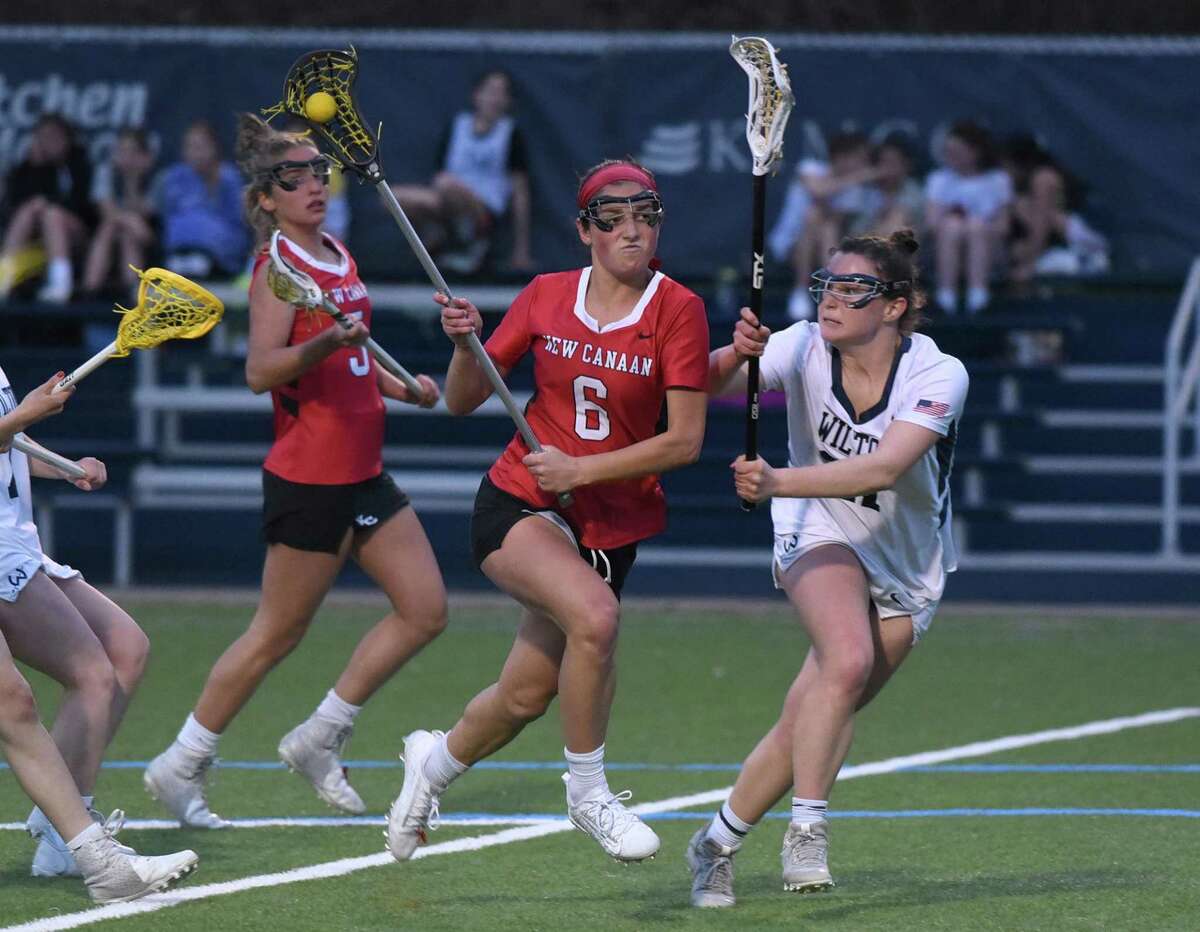 New Canaan’s Kaleigh Harden (6) drives to the net while Wilton’s Whitney Hess (27) defends on April 13.