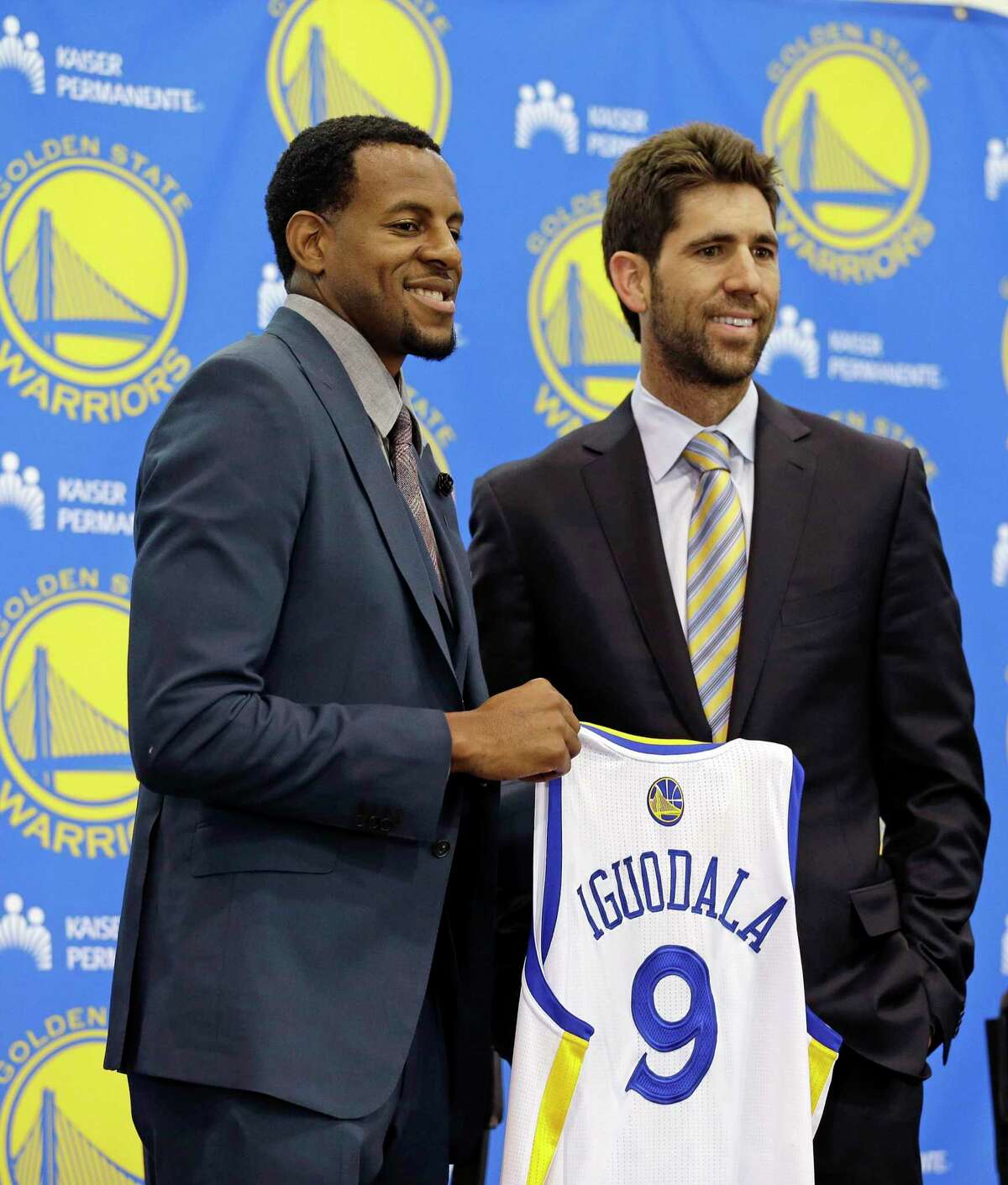 Andre Iguodala, left, poses with Golden State Warriors general manager Bob Myers, right, after being introduced by the NBA basketball team at a news conference on Thursday, July 11, 2013, in Oakland, Calif. The Warriors formally introduced their prized free agent acquisition who spurned the Denver Nuggets to join the rejuvenated Warriors on a four-year, $48 million deal. (AP Photo/Eric Risberg)