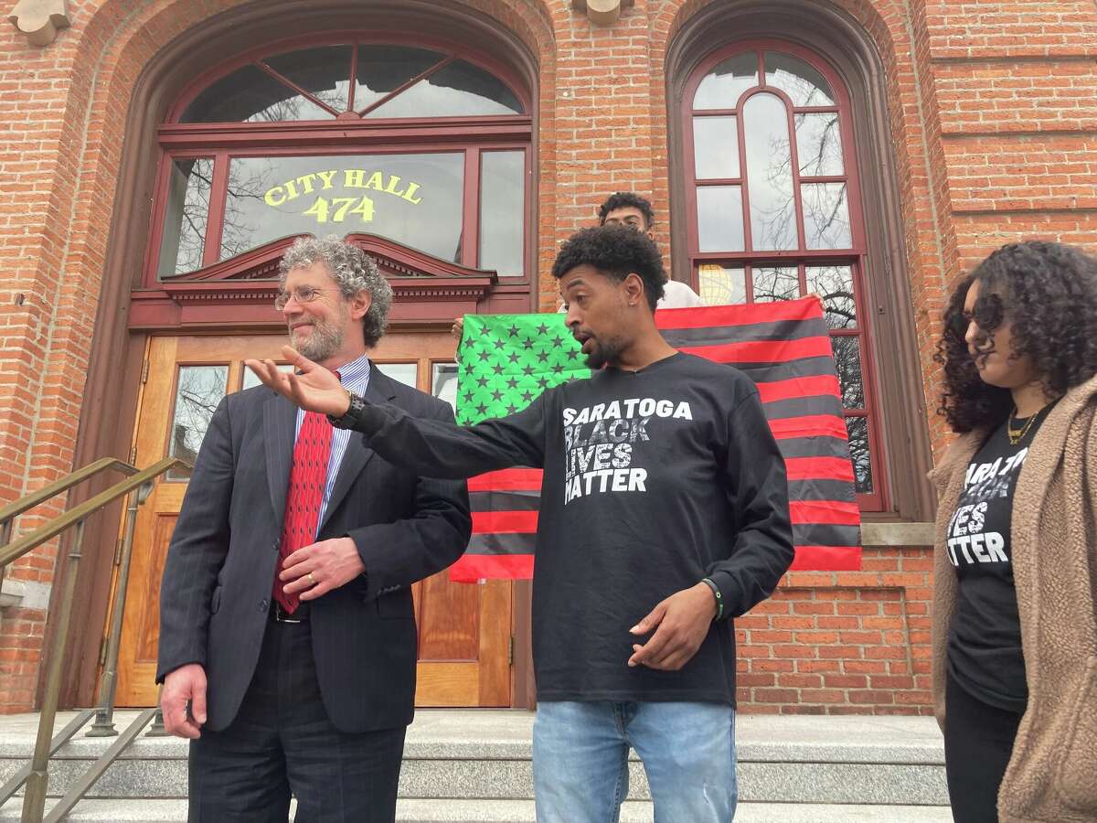Attorney Mark Mishler, left, stands with his client Lexis Figuereo, center, with Black Lives Matter activist Samira Sangare on the steps of City Hall on Tuesday, April 14, 2022.