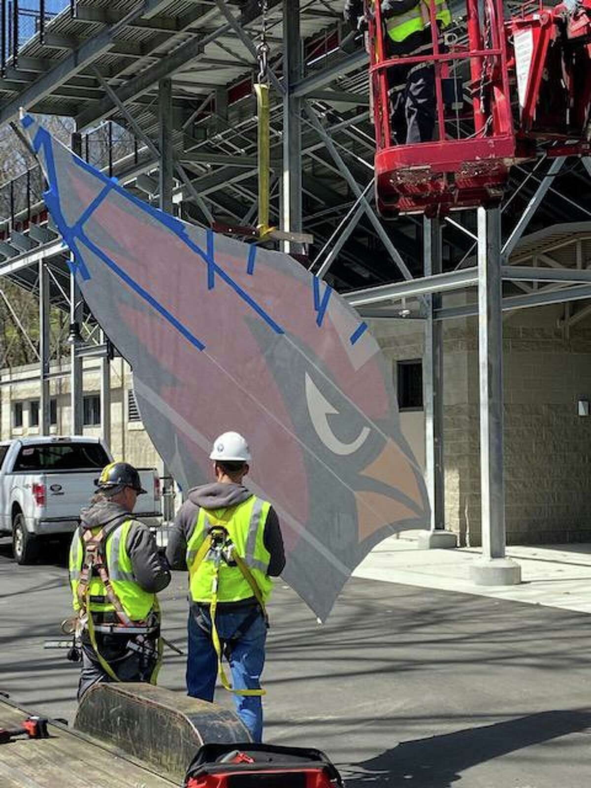 Crews utilize an aerial platform to haul a large cardinal above the bleachers of Greenwich High School's Cardinal Stadium Monday, April 11, 2022.