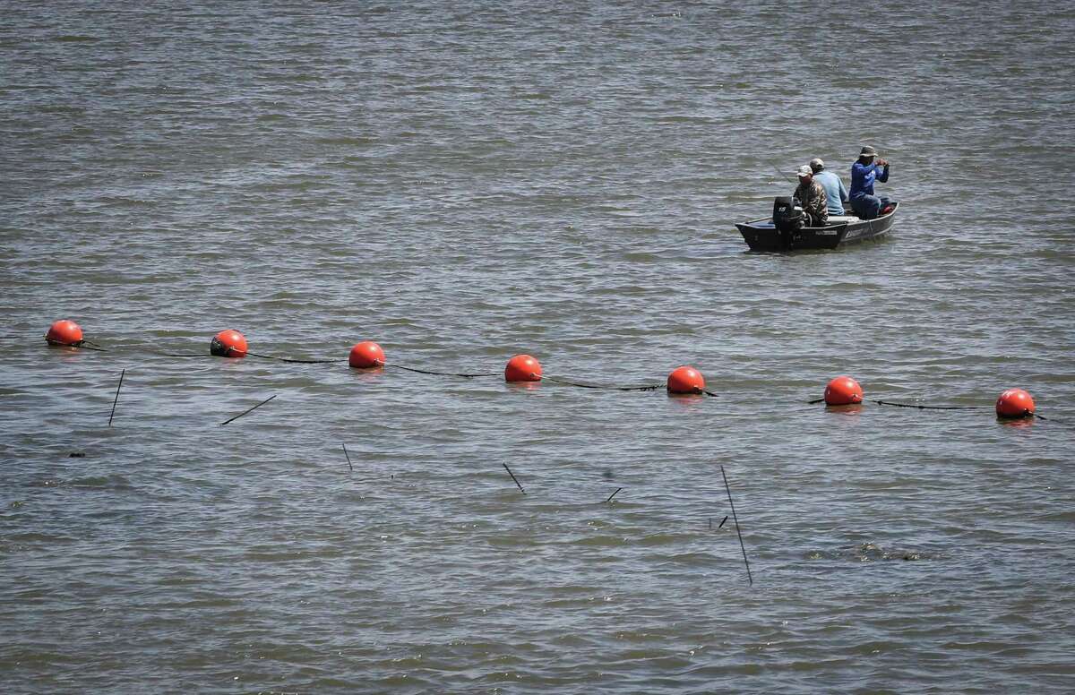 Men fish next to the San Jacinto River Waste Pits Superfund site on Thursday, April 14, 2022, in Channelview.