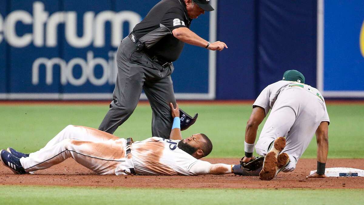 The Tampa Bay Rays' Manuel Margot slides into second base and collides with umpire Hunter Wendelstedt (21). Oakland shortstop Elvis Andrus tags Margot out in the second inning. (Ivy Ceballo/Tampa Bay Times/TNS)