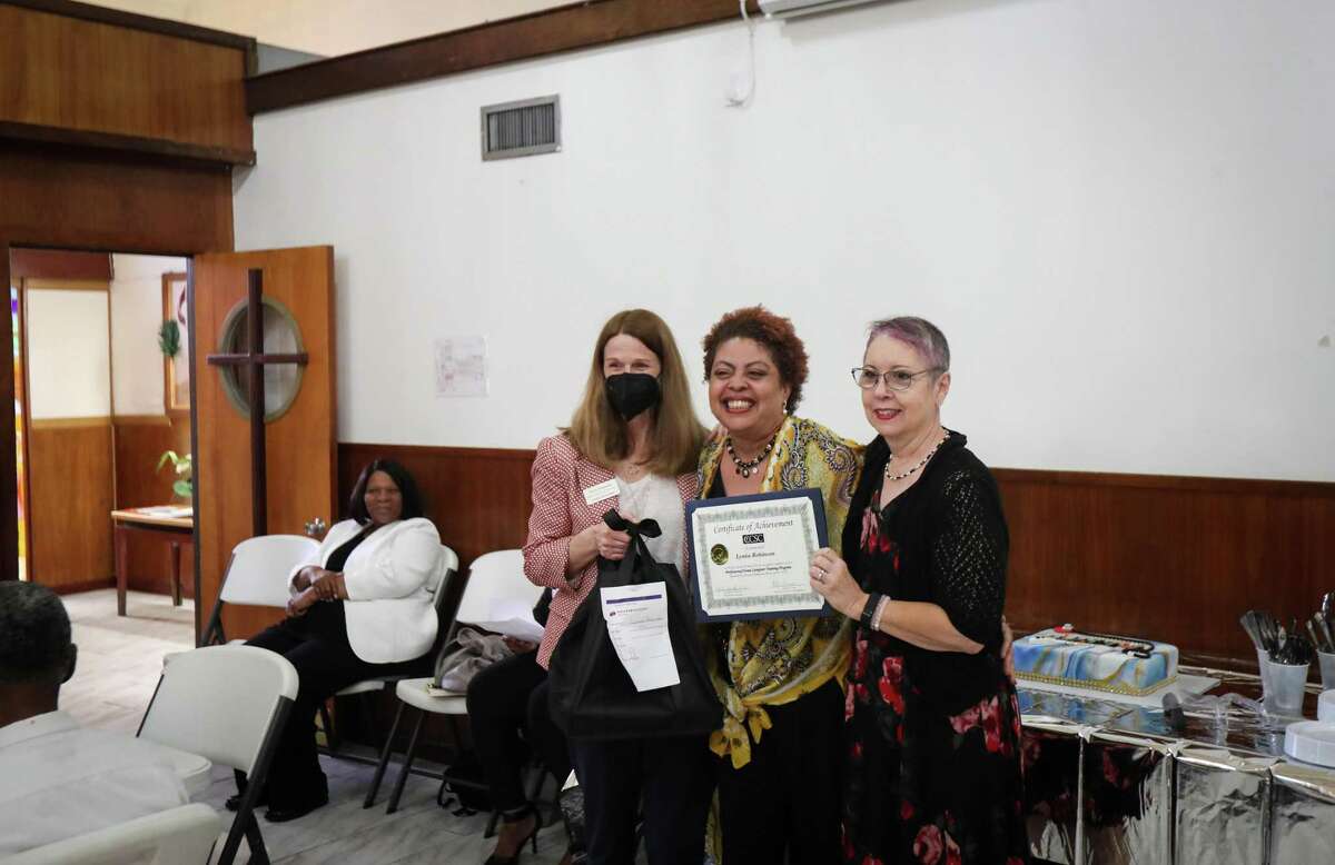 Lynita Robinson, center, smiles for a photo with Tracy Simmons, left, and Maureen Brunetti, as she receives her certificate of completion for the Christian Community Service Center home caregiving training program during a ceremony Wednesday, April 6, 2022, at Boynton United Methodist Church in Houston. Robinson’s mom recently broke her arm caring for Robinson’s grandmother, and now Robinson is caring for her. Robinson said she thinks about what her family members went through and how her knowledge can help her family.