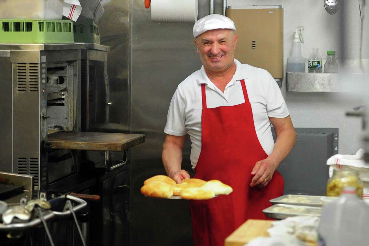 Mark Bezhi, a baker at Cka ka Qellu, shows samuna bread fresh out of the oven on Clark Street in downtown in Stamford, Conn., on Tuesday April 12, 2022. Cka ka Qellu in an Albanian restaurant that just opened in March.