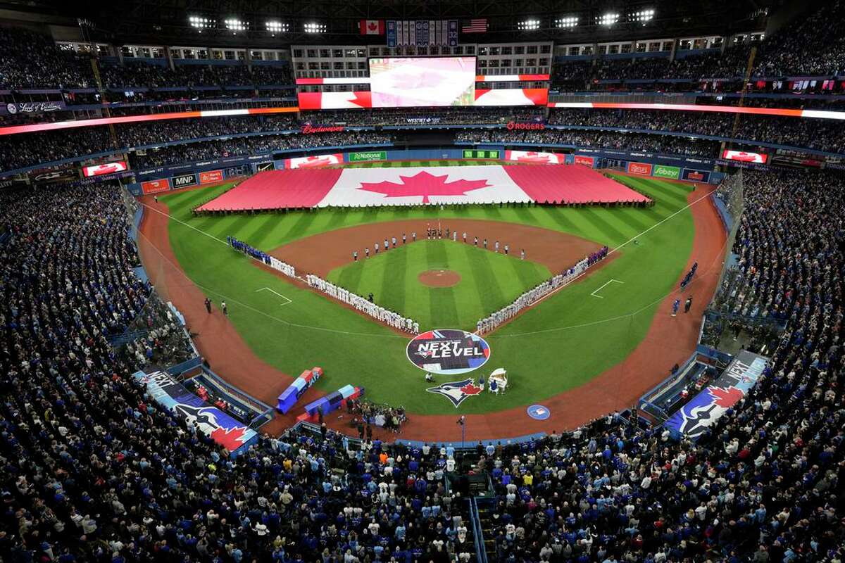 Members of the Canadian Armed Forces carry a Canadian flag onto the outfield before a baseball game between the Toronto Blue Jays and the Texas Rangers on Friday, April 8, 2022, in Toronto. (Nathan Denette/The Canadian Press via AP)