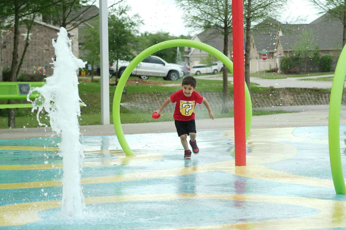 Ivan Alvarez runs through a hoop spray apparatus at the splash pad at Centennial Park in Pearland.