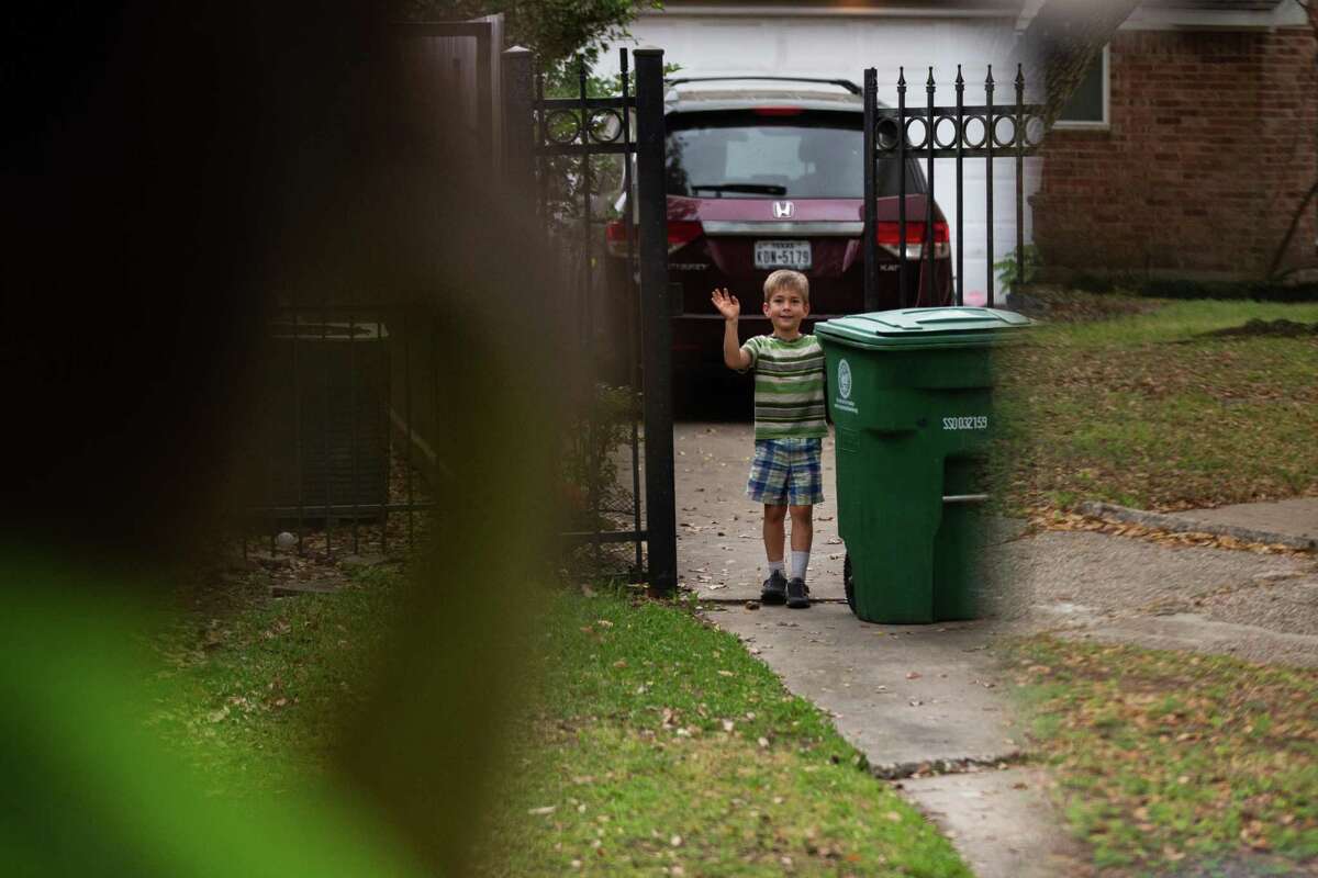 A child waiting to bring in a trash can back to his home, greets City of Houston Solid Waste Dept. trash truck driver Anthony Senegal, 56, Tuesday, March 29, 2022, in Houston.
