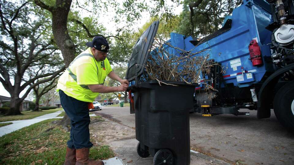 City of Houston Solid Waste Dept. trash truck driver Anthony Senegal, 56, places an orange tag to let the owner know that small branches, and leaves must not be placed in the automated garbage cans. They must be put in city-approved compostable bags, Tuesday, March 29, 2022, in Houston.