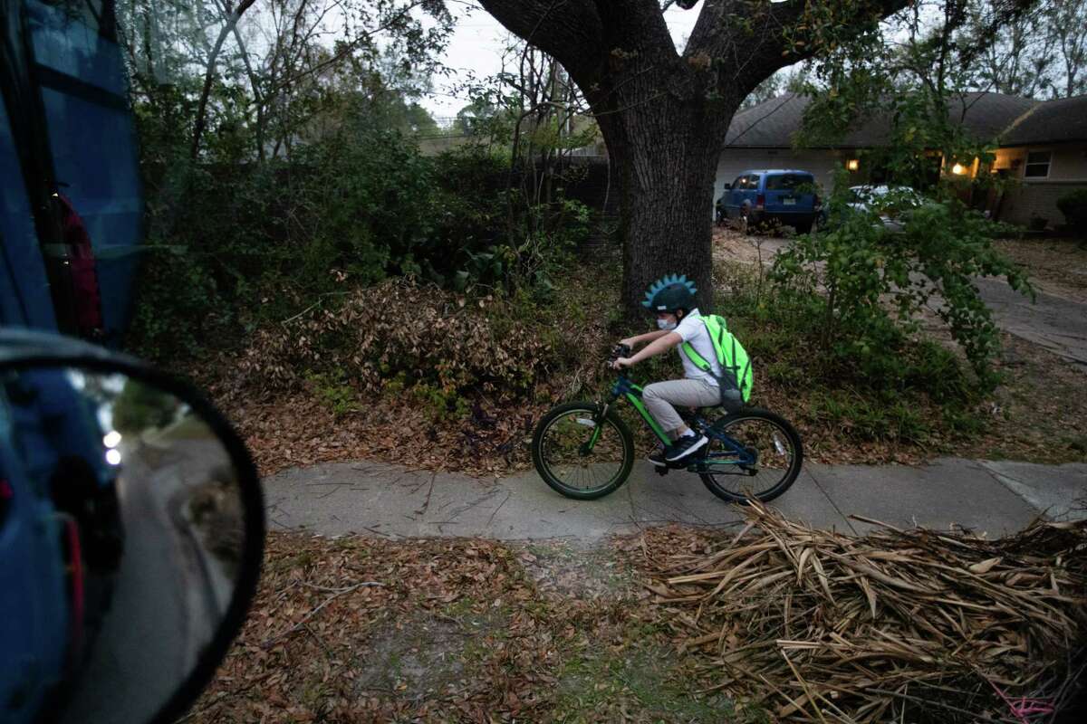 A child rides a bicycle by a City of Houston trash truck on his way to school in the morning, Tuesday, March 29, 2022, in Houston.