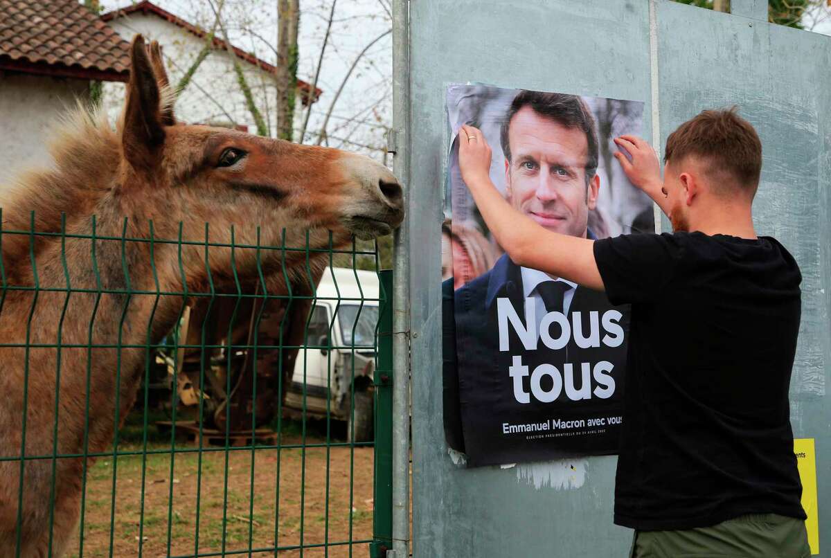 An employee of the France Affichage company glues a campaign poster for the re-election President Emmanuel Macron in Ahetz, France, on Friday. The country will vote April 24 in the second round of the presidential election.