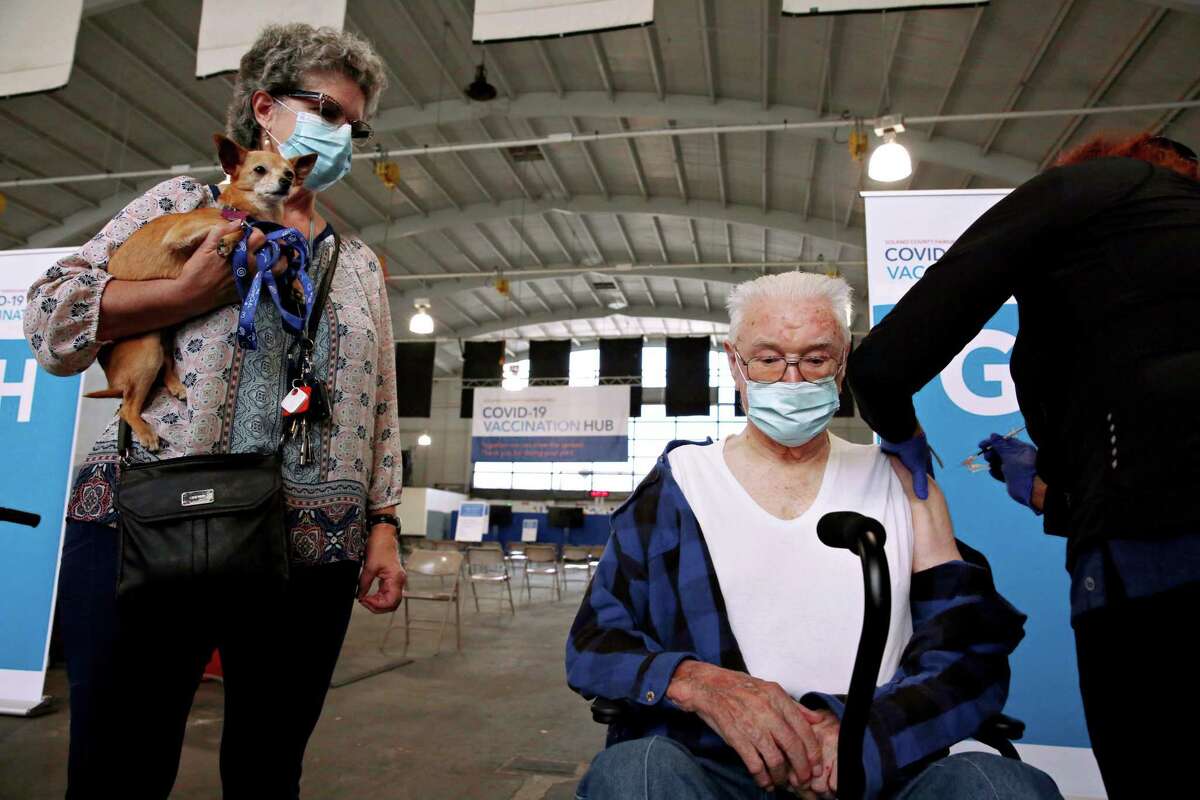 Henri Louvigny receives a Pfizer booster as his daughter looks on at the mass vaccination site at the Solano County Fairgrounds in Vallejo, Calif.