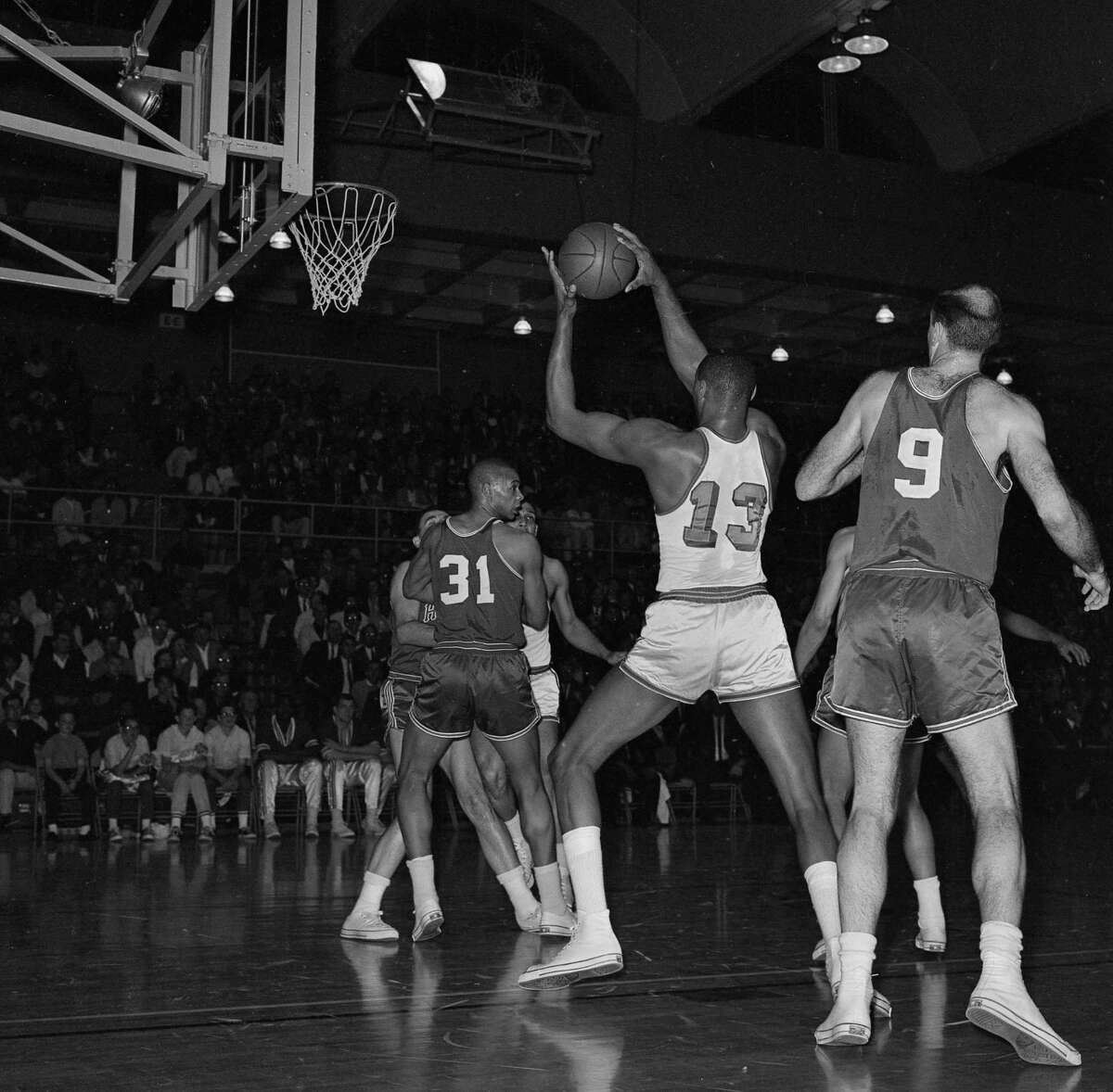 Wilt Chamberlain pulls down a rebound between the Hawks’ Zelmo Beatty (31) and Bob Pettit during Game 1 of the 1964 Western Conference finals on April 1 at USF’s War Memorial Gymnasium.
