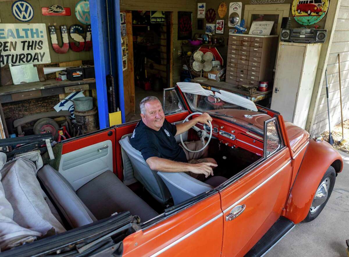 James Oliver poses in one of his five Volkswagens at his San Antonio home. Oliver owns three Beetles and two Buses.