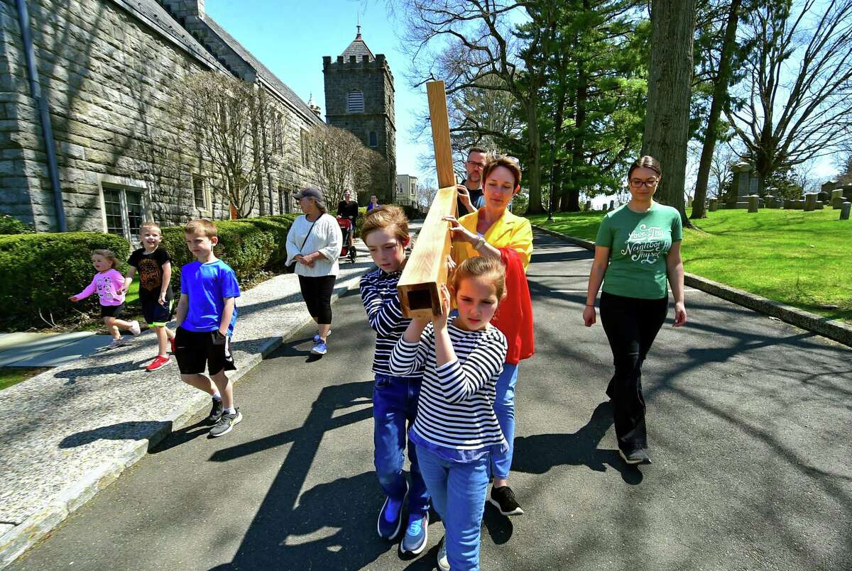 First Congregational Church congregants Susan Elliott-Bocassi, and her children Nico, 9, and Alida, 8, start a walk with a wooden cross from the church to Greenwich Point Park on Good Friday in Greenwich, Conn., on Friday April 15, 2022. Pastor Patrick Collins and Assistant Pastor Cydney Van Dyke led a short service before the walk began.