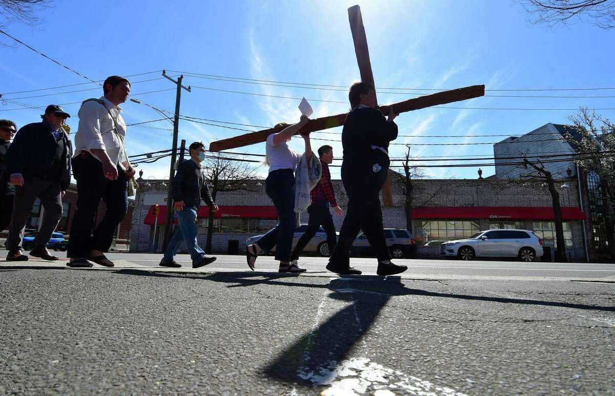 Congregants from Darien First Congregational Church and St. Luke Parish Darien gather to walk with a wooden cross along Post Road on Good Friday in Darien, Connecticut on Friday, April 15, 2022. About 50 people attended walked to 13 stops along the route which represent the 13 stations of the cross. The prayers read at each stop were tailored to each location, such as one for the fire department and one for the train station.