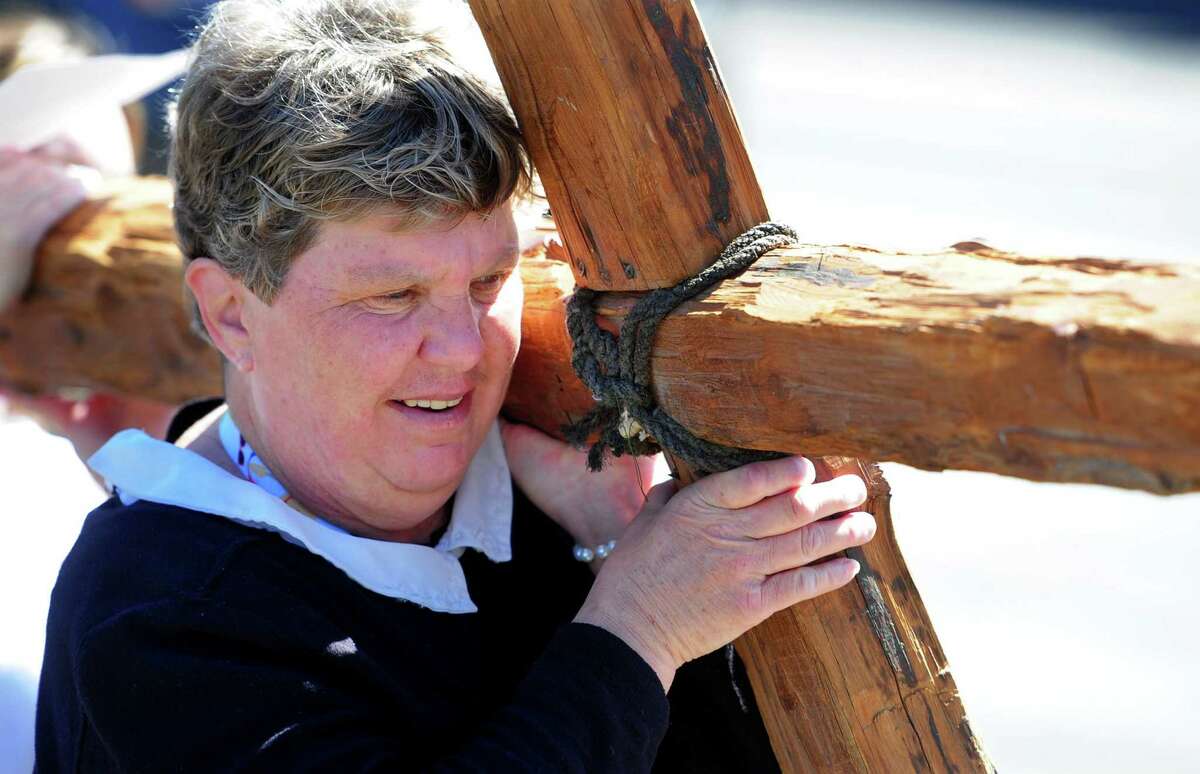 Maureen Eckrich volunteers to carry the cross as she and congregants from First Congregational Church of Darien and St. Luke's Parish Darien gather to walk along Post Road on Good Friday in Darien, Connecticut, Friday, April 15 2022. About 50 people walked to 13 stops along the route which represent the 13 stations of the cross.  The prayers read at each stop were tailored to each location, such as one for the fire department and one for the train station.