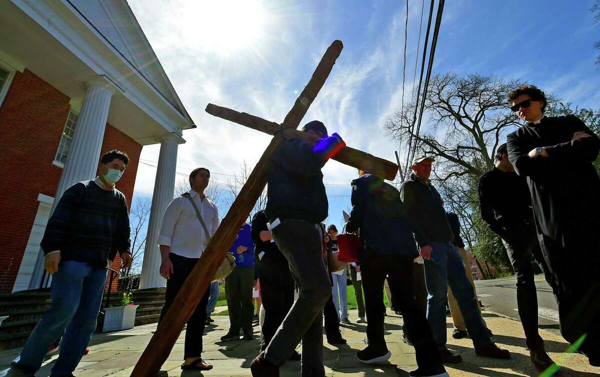 Steve Knowles first volunteers to carry a roughly hewn wooden cross with congregants from the First Congregational Church of Darien and St. Luke's Darien Parish, who gathered to walk with the cross along Post Road on Good Friday in Darien, Connecticut, Friday, April 15, 2022. About 50 people walked 13 stops along the route that represent the 13 stations of the cross. The prayers read at each stop were tailored to each location, such as one for the fire department and one for the train station.