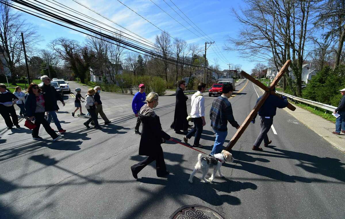 Congregants from Darien First Congregational Church and St. Luke Parish Darien gather to walk with a wooden cross along Post Road on Good Friday in Darien, Connecticut on Friday, April 15, 2022. About 50 people attended walked to 13 stops along the route which represent the 13 stations of the cross.  The prayers read at each stop were tailored to each location, such as one for the fire department and one for the train station.