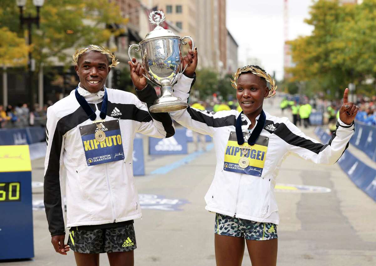 Benson Kipruto and Diana Kipyogei of Kenya react after winning the men's and women's divisions of the 125th Boston Marathon on Oct. 11, 2021 in Boston, Mass.