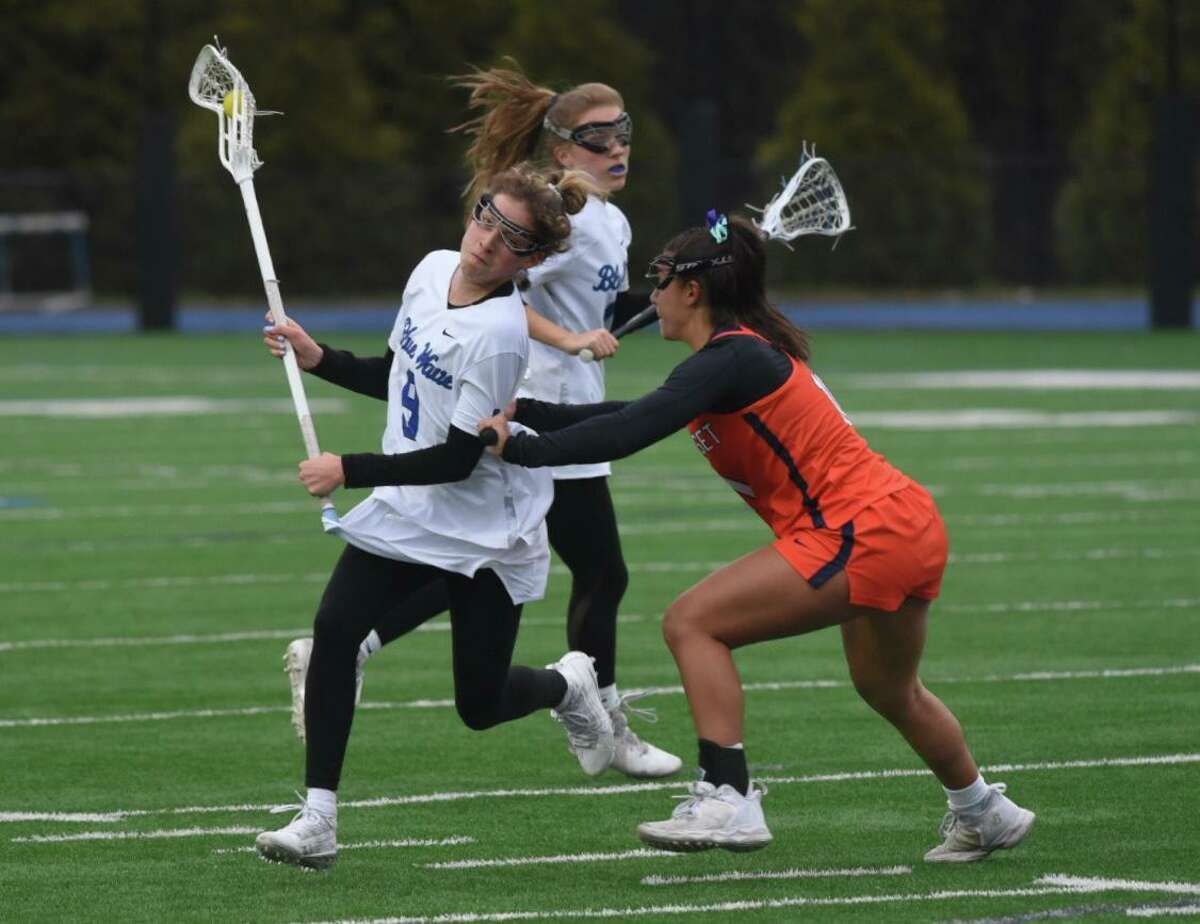 Darien’s Ceci Stein (9) is defended by Manhasset’s Nicole Giannakopoulos (11) during a girls lacrosse game on Wednesday, April 6, 2022 in Darien, Conn.
