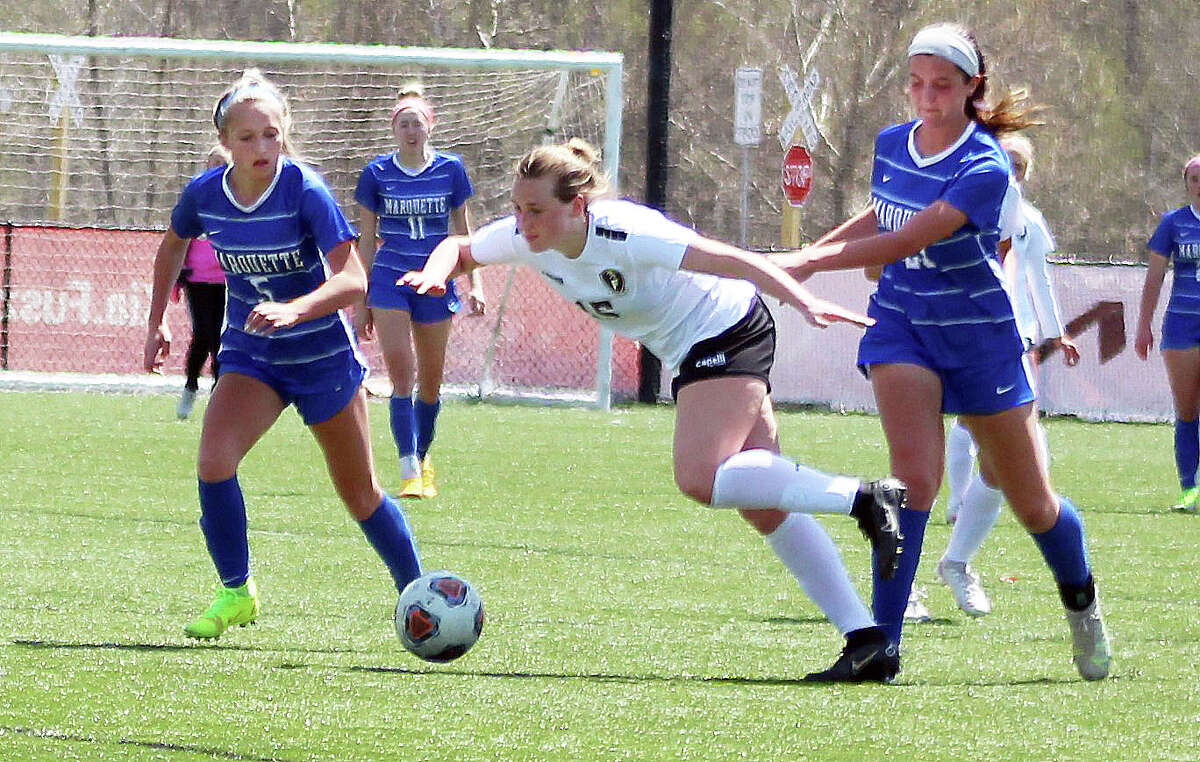 Taylor Branch of Farmington, center, tries to keep her balance as she attempts to get around Marquette's Clare Antrainer (5) and Jillian Nelson Saturday at the Lou Fusz Soccer Complex.