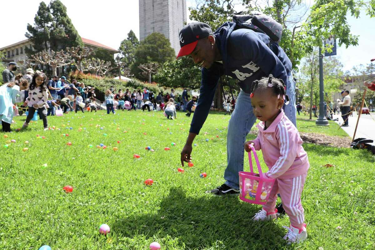 Jamontae Robinson, 26, helps his daughter Ayva Robinson, 1, of Emeryville, search for eggs during her first Easter egg hunt at the 28th annual Eggster event at UC Berkeley on Saturday, April 16, 2022, in Berkeley, Calif. Robinson discovered the event from the website 510families.com. “It saved Easter,” Robinson said. “That’s my favorite site right now.”