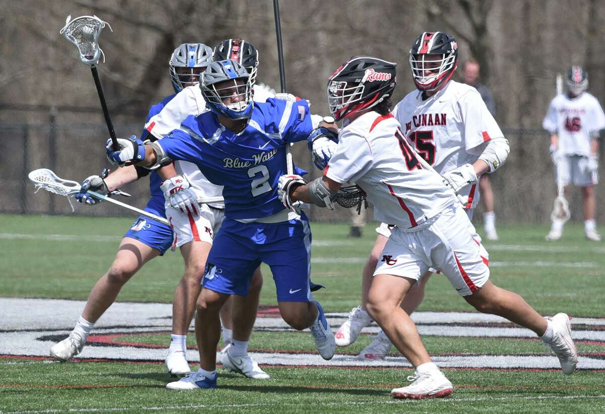Darien's Riley Strub (2) controls the ball while New Canaan's William Haynes (48) tries to knock it loose during a boys lacrosse game in New Canaan on Saturday, April 16, 2022.