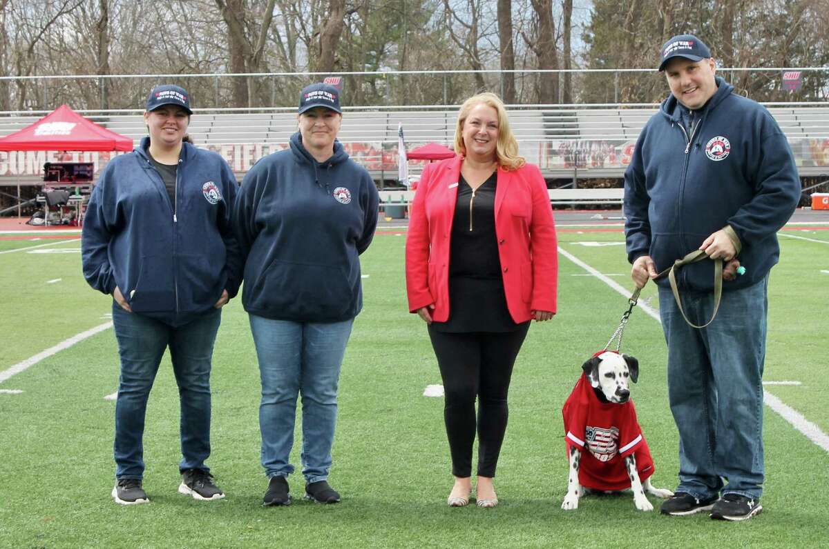 The Sacred Heart University Men’s lacrosse team recently honored the Long Island based non-profit, national organization, and 501(c)(3) charitable organization, Paws of War for their work, before the team’s military appreciation game, Saturday, April 9, against the Merrimack College at Campus Field, that is located at the school, at 5151 Park Ave. in Fairfield. The final score of the game was, 11-8, in favor of Merrimack, which is located in North Andover, Mass. Pictured in the photo, from the left to the right are: Casey Rosenhaus, of Paws of War, Kelli Porti, a U.S. Army Veteran, and community outreach liaison for Paws of War, Judy Ann Riccio, director of athletics for the Sacred Heart University, and Stephen Porti, who is retired from the New York City Fire Department, FDNY, and who is also a Paws of War Volunteer.