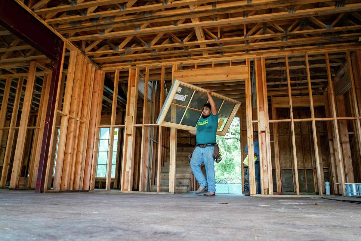 Building more efficient homes with smaller floor plans in urban settings could help lower emissions from the residential sector. In this 2021 photo, Jose Hernandez carries a new window inside a custom home in West University Place.