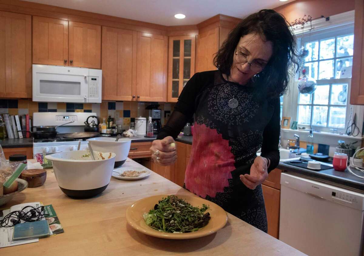 Caroline Barrett squeezes lemon on Asian chicken salad she’s preparing in her kitchen on Tuesday, April 12, 2022 in Delmar, N.Y.