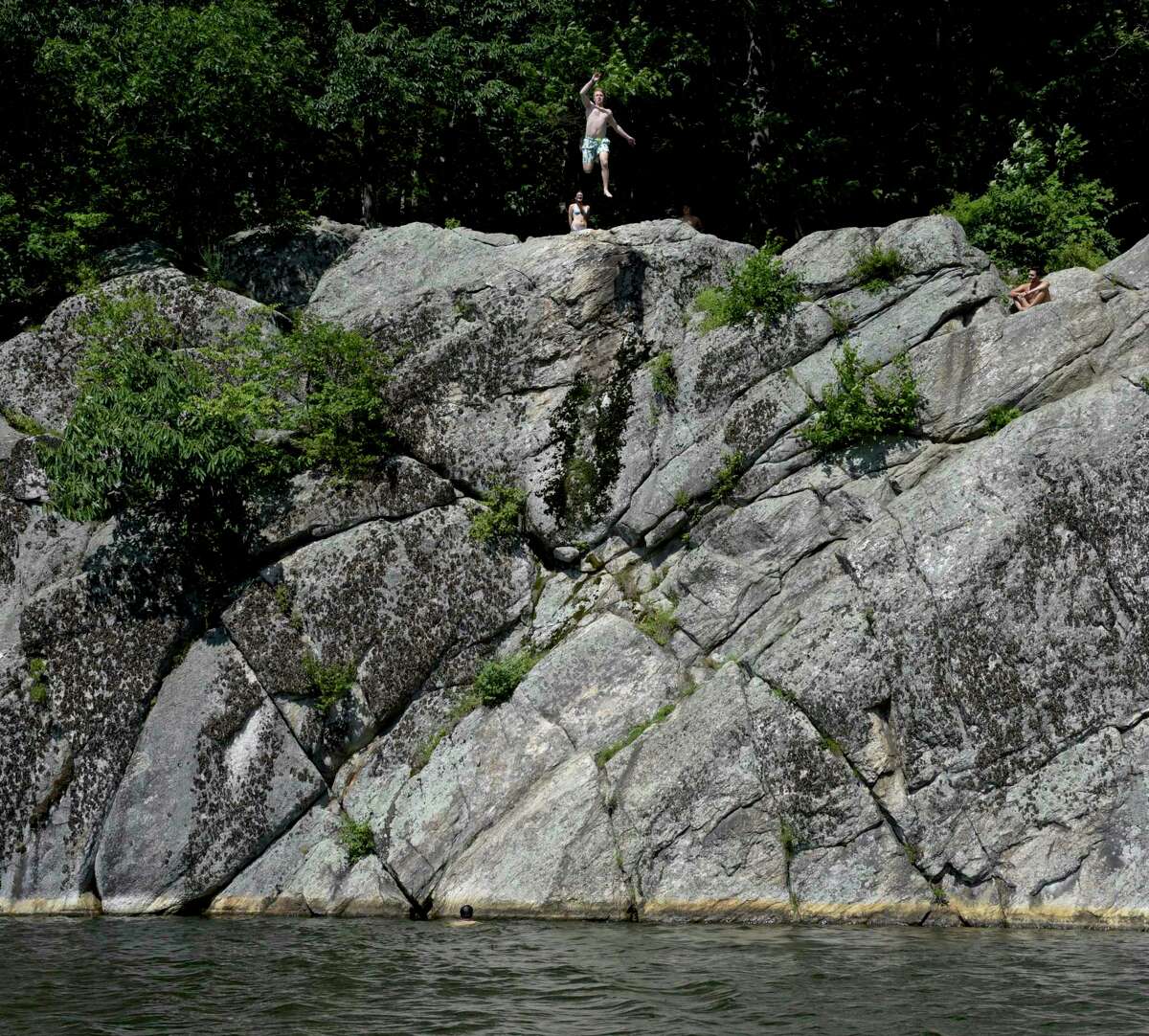 People jump from the cliffs in Richardson Park into Mamanasco Lake. Friday, July 30, 2021, in Ridgefield, Conn.