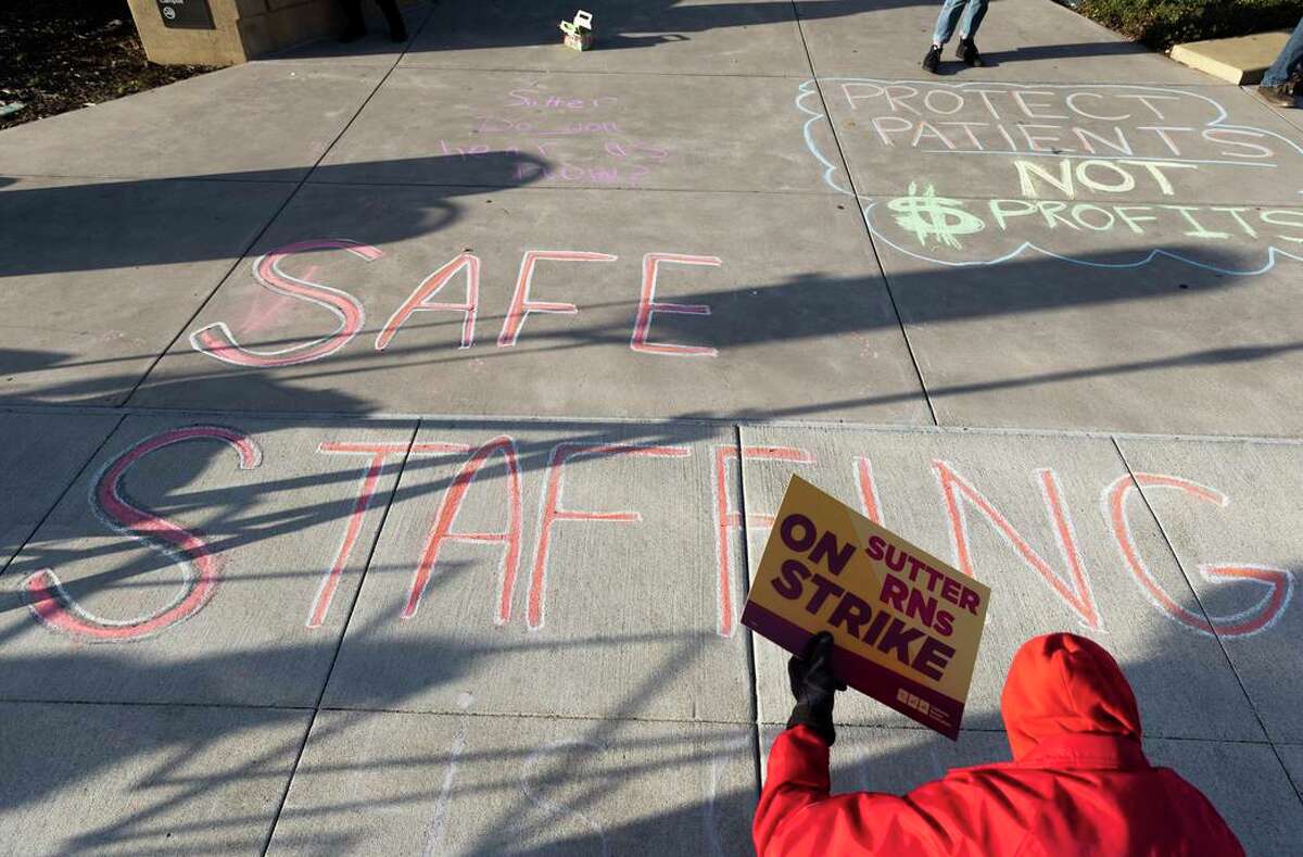 On a one-day strike, California Nurses Association members write chalk messages outside of Alta Bates Summit Medical Center in Oakland.