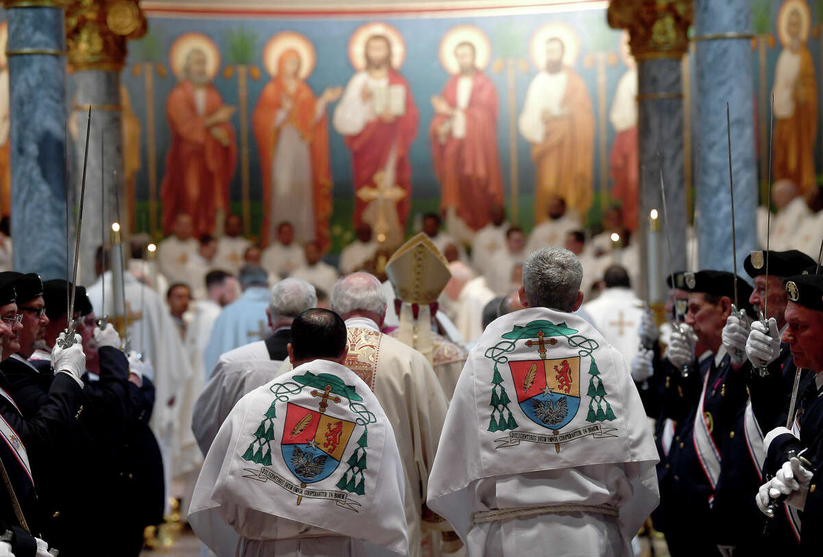Servers who aid Bishop David Toups during mass wear special capes embroidered with his diocesan crest, as seen here during the Holy Week Chrism Mass Tuesday night at St. Anthony Cathedral Basilica. Photo made Tuesday April 12, 2022. Kim Brent/The Enterprise