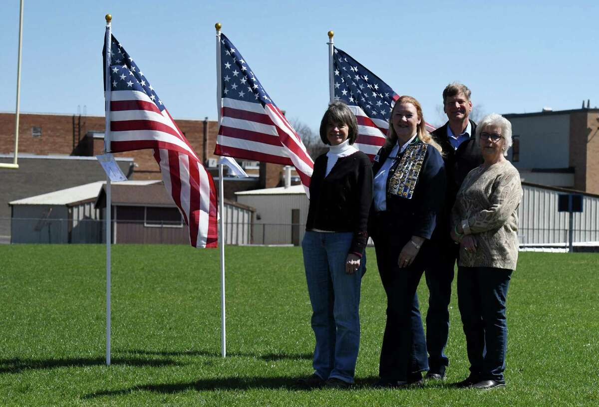 Schaghticoke Field of Honor organizers; Marilou Pudiak-Town, left, Sandy Zerrillo, Russ Greenman and Lynn Keyes, right, stand with flags in the Hoosic Valley Central School football field where the group plans to display 1,000 flags over the Memorial Day weekend to support and remember veterans on Monday, April 18, 2022, in Schaghticoke, N.Y. Organizers are seeking sponsors to honor current military members, fallen servicemen & women and all veterans, with proceeds to benefit Patriot Flight, Inc.