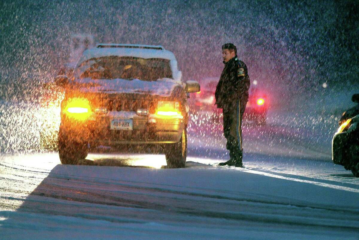 As heavy snow falls, a Trumbull police officer investigates a minor accident at the entrance to the Merritt Parkway at Park Ave in Trumbull, Conn., on Thursday, Nov. 15, 2018. The snow which started falling in the later afternoon, caused many cars to be stuck along Park Ave and other roads around the area.
