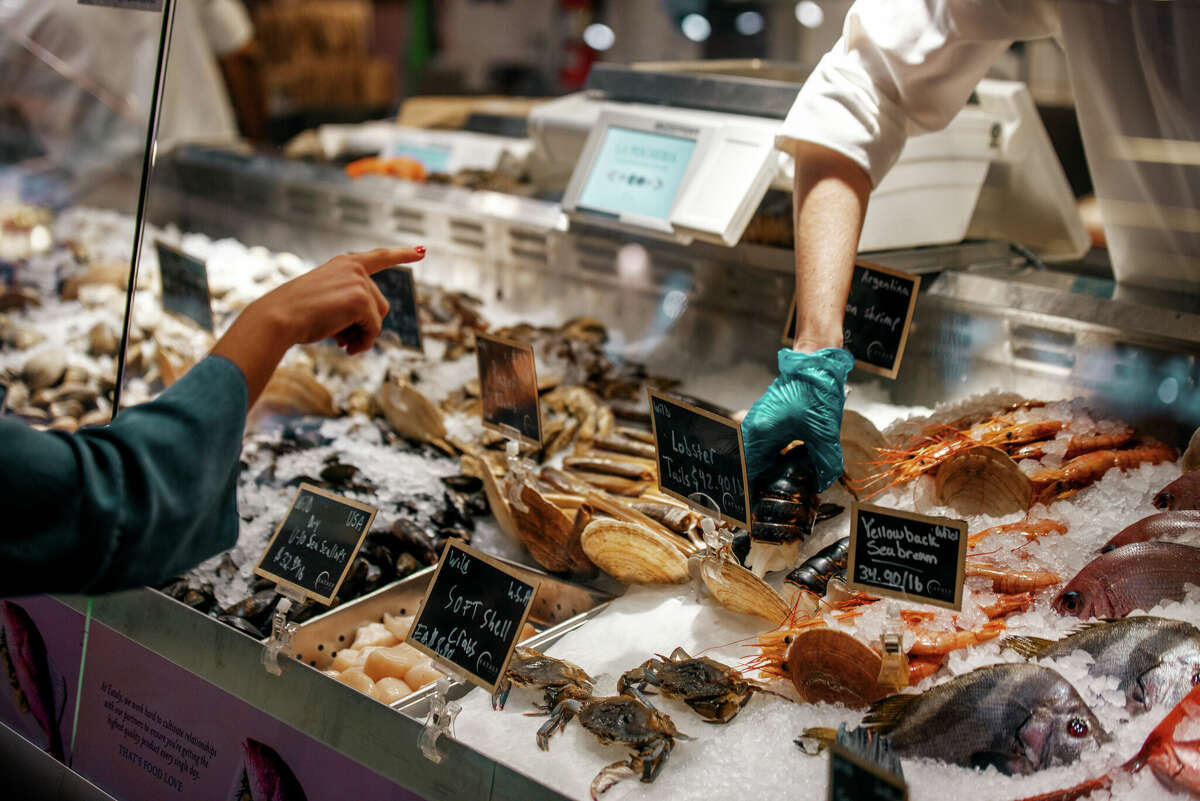 Fresh soft shell crab, lobster tail and other seafood on display at an Eataly fish counter.