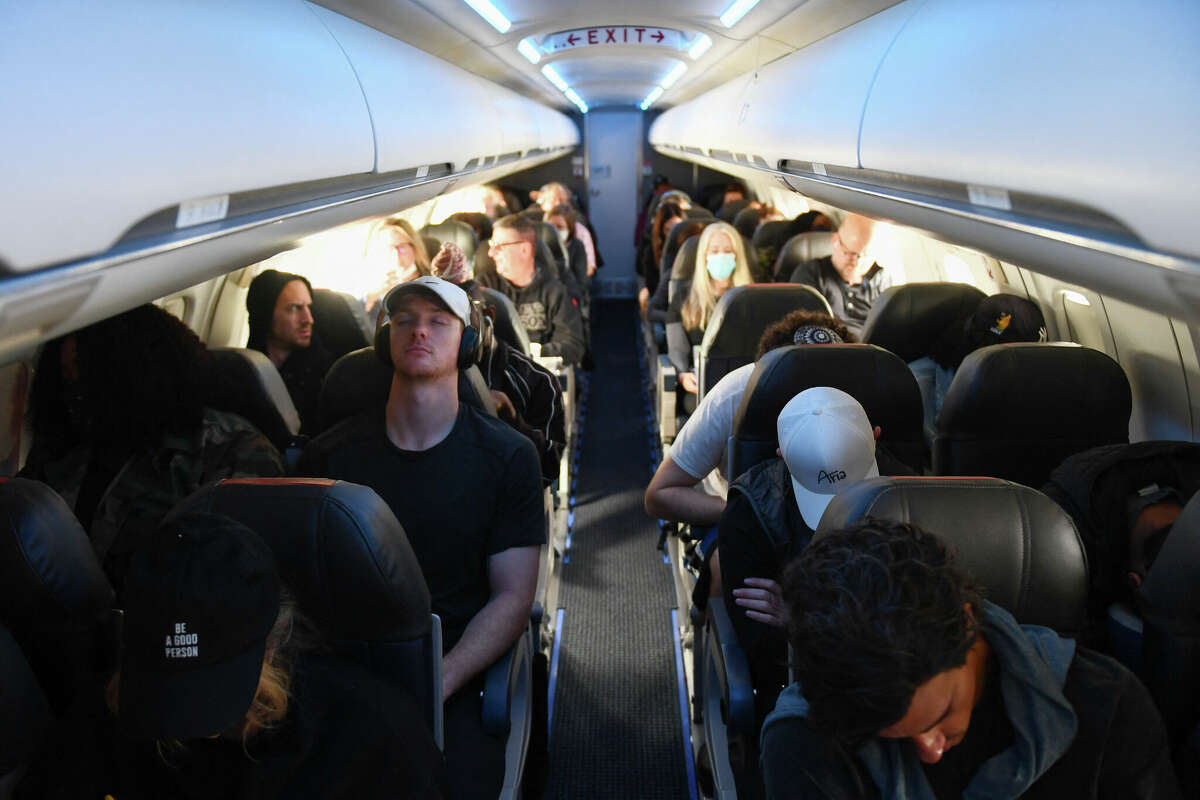 Passengers, some not wearing face masks after a federal judge struck down public transportation mandates, sit Tuesday during an American Airlines flight.