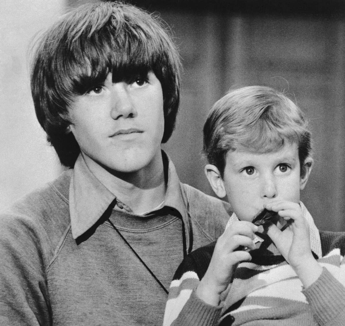 Timmy White, 5, sits on the lap of Steven Stayner, 14, and tries to blow a balloon up during press conference after their rescue in 1980.