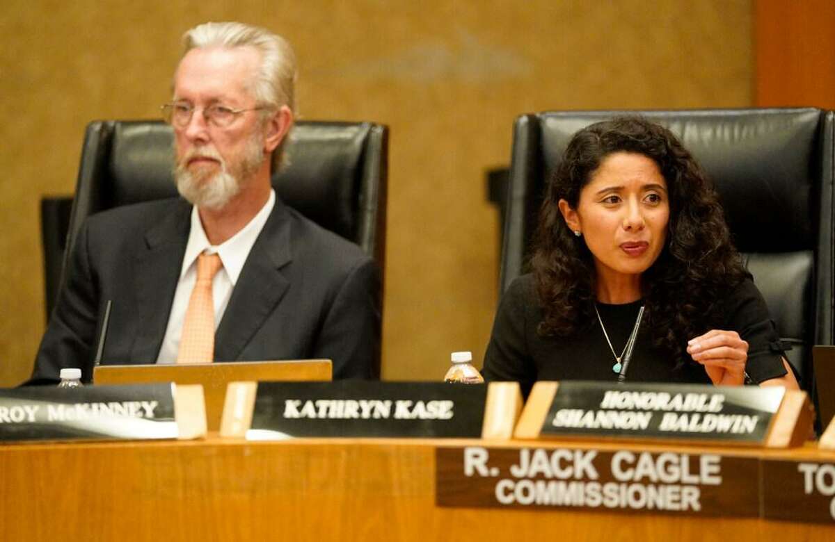 W. Troy McKinney, left, as Harris County Judge Lina Hidalgo speaks during the Harris County Bail Bond Board meeting Wednesday, April 13, 2022, in Houston. The board voted on a proposal to set minimum 10 percent fee on bail bonds.