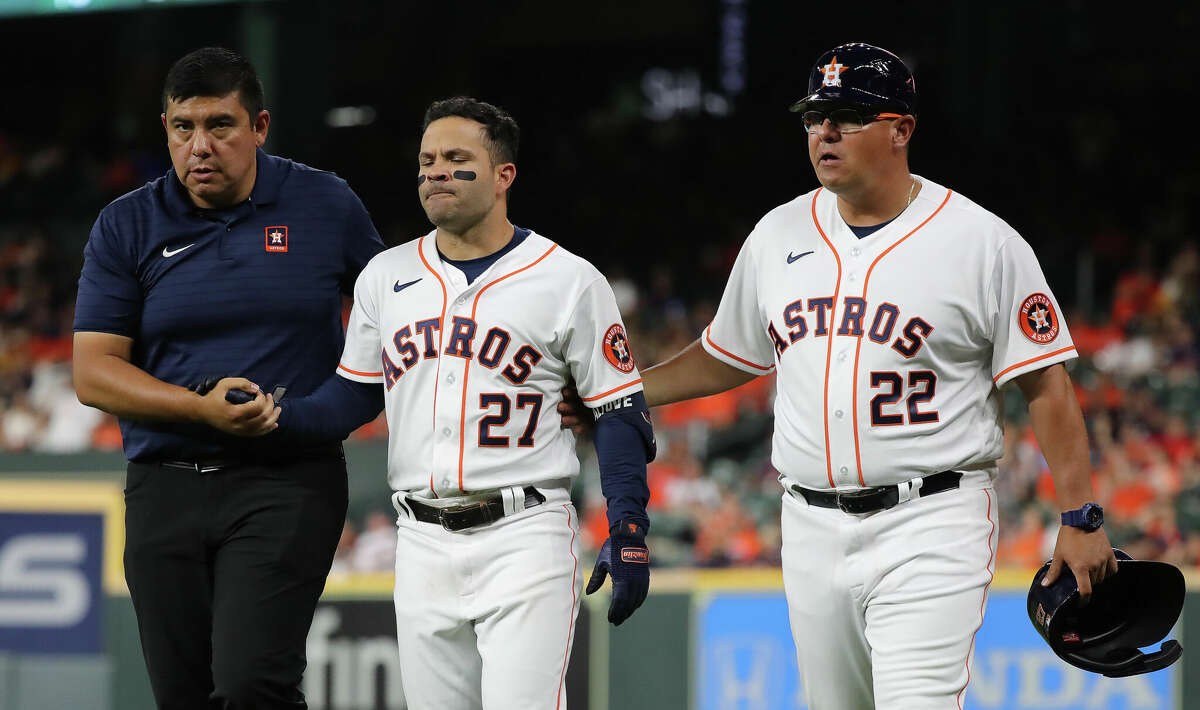 Jose Altuve of the Houston Astros is helped off the field by first base coach Omar Lopez and a trainer after injuring himself running out an infield hit in the eighth inning against the Los Angeles Angels at Minute Maid Park on April 18, 2022 in Houston.