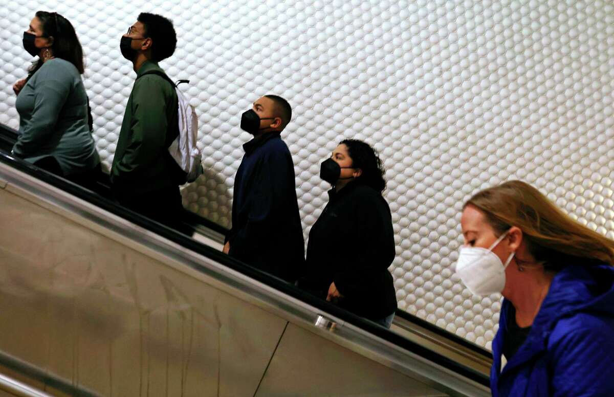 The swell of COVID cases fueled by the omicron subvariant that has yet to peak. Health officials say the curve’s rise and fall are harder to predict. People wearing masks ride the escalator and walk up stairs from the platform at Powell Street BART station on Tuesday, April 19, 2022 in San Francsico, Calif.