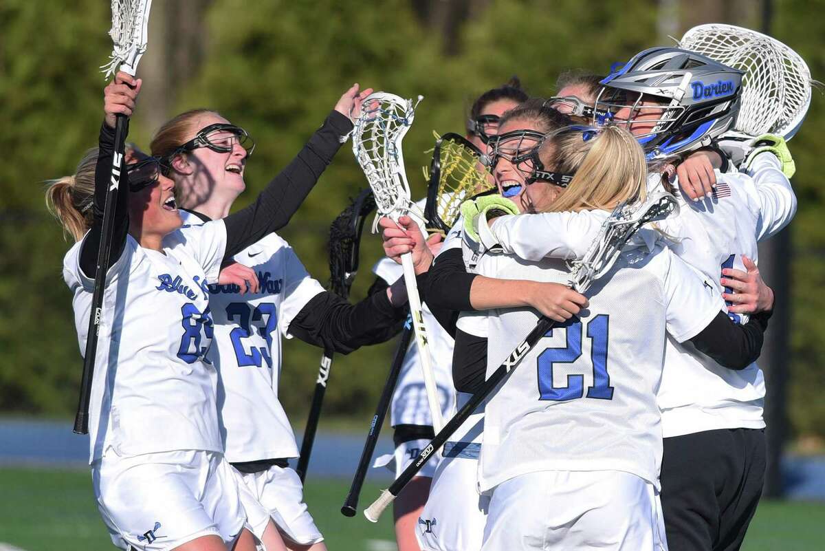 Darien players celebrate after defeating New Canaan 15-11 in a girls lacrosse game in Darien on Tuesday, April 19, 2022.