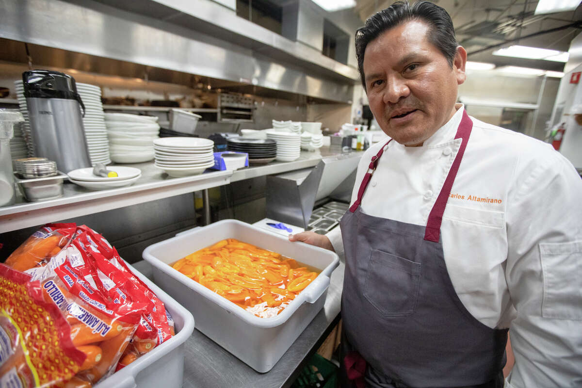Šefas Carlosas Altamirano savo perujietiškame restorane „La Costenera“ Half Moon Bay Kalifornijoje demonstruoja keletą ahi amarillo Peru čili, kurį naudoja su troškiniais.  2022 m. balandžio 12 d.