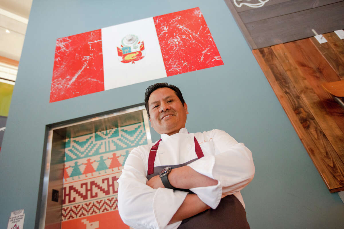 Chef Carlos Altamirano poses in front of a Peru flag at his Peruvian restaurant La Costanera in Half Moon Bay, Calif., on April 12, 2022.