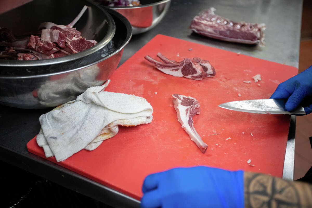 A line cook prepares some lamb at the Peruvian restaurant La Costenera in Half Moon Bay Calif.  on April 12, 2022.
