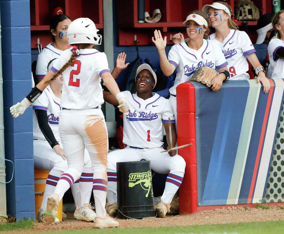 Oak Ridge’s Ariel Redmond, center, gives Cheyenne Conway a high-five after scoring on a wild pitch by College Park starting pitcher Arriana Wright in the third inning of a District 13-6A high school softball game at Oak Ridge High School, Tuesday, April 19, 2022.