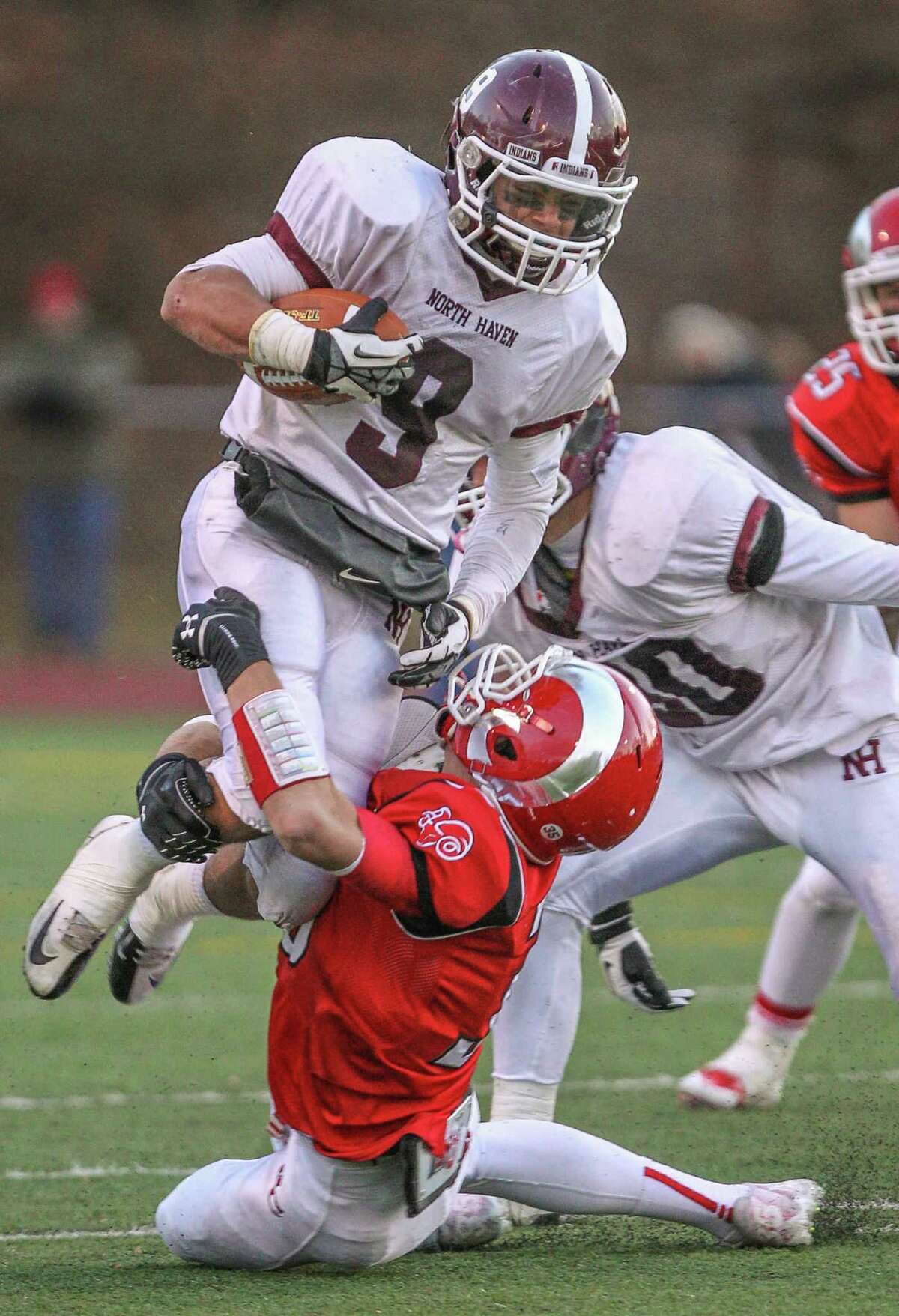 North Haven Running Back Cole Pecora tries going over the top of a New Canaan defender during the Indians Class L Semi Final loss to the Rams